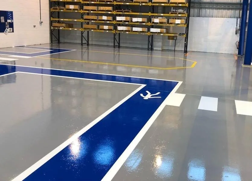 Industriële ruimte met een doorlopende harsvloer en blauw-witte verkeersmarkering